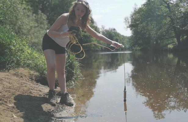 Maddy Wright inserting testing probe into river. 