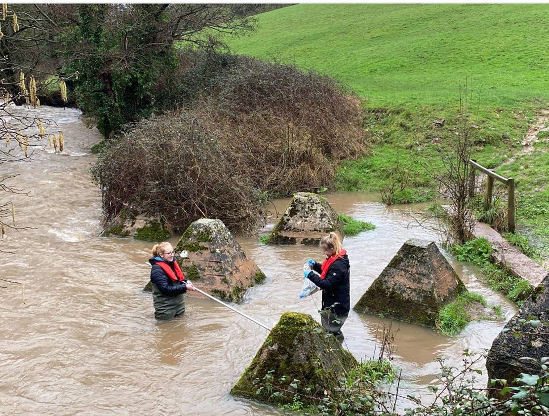 Researchers stand in a river to take measurements.